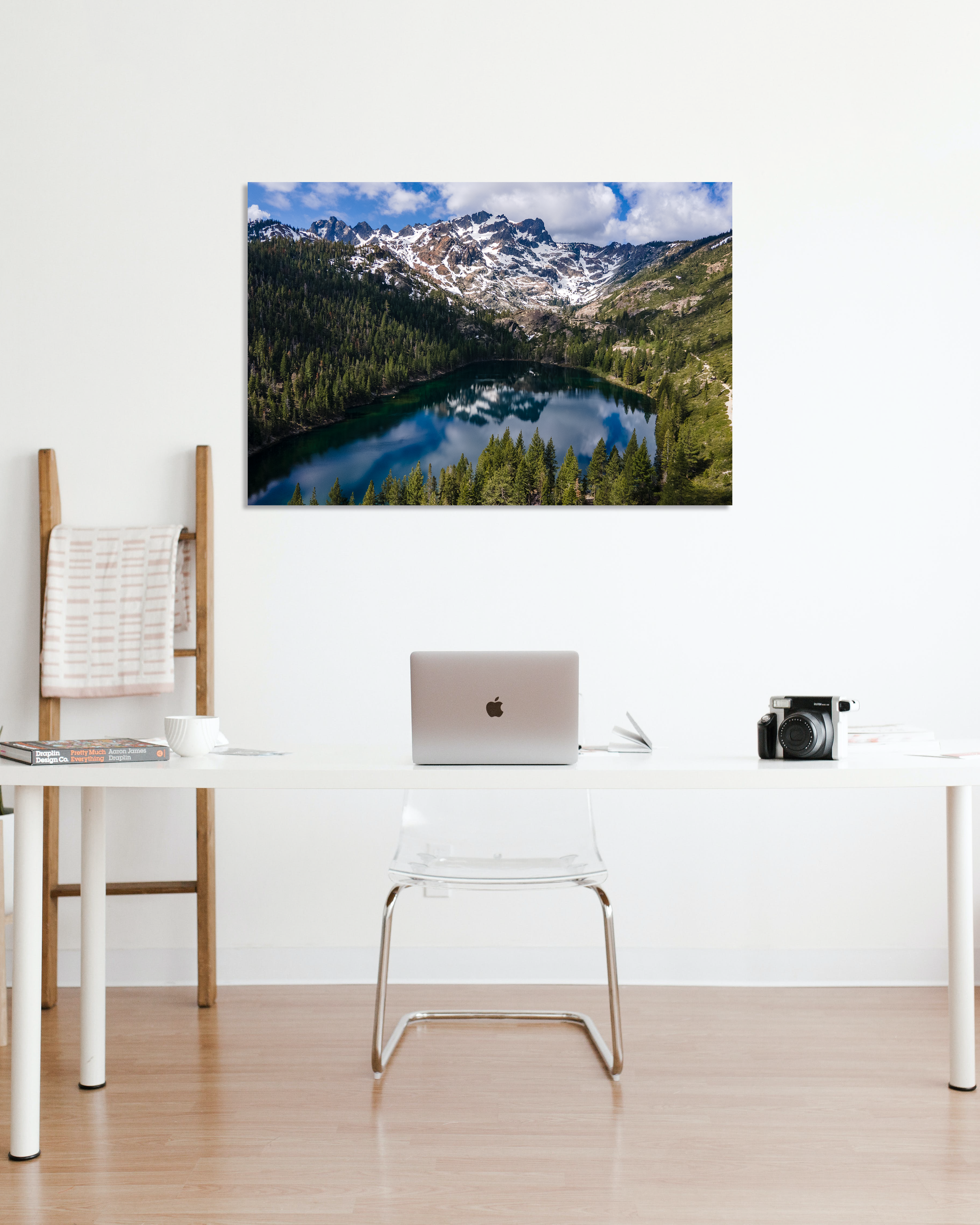 Behind a small office desk hangs a fine art photo with snow capped peaks above an alpine lake.