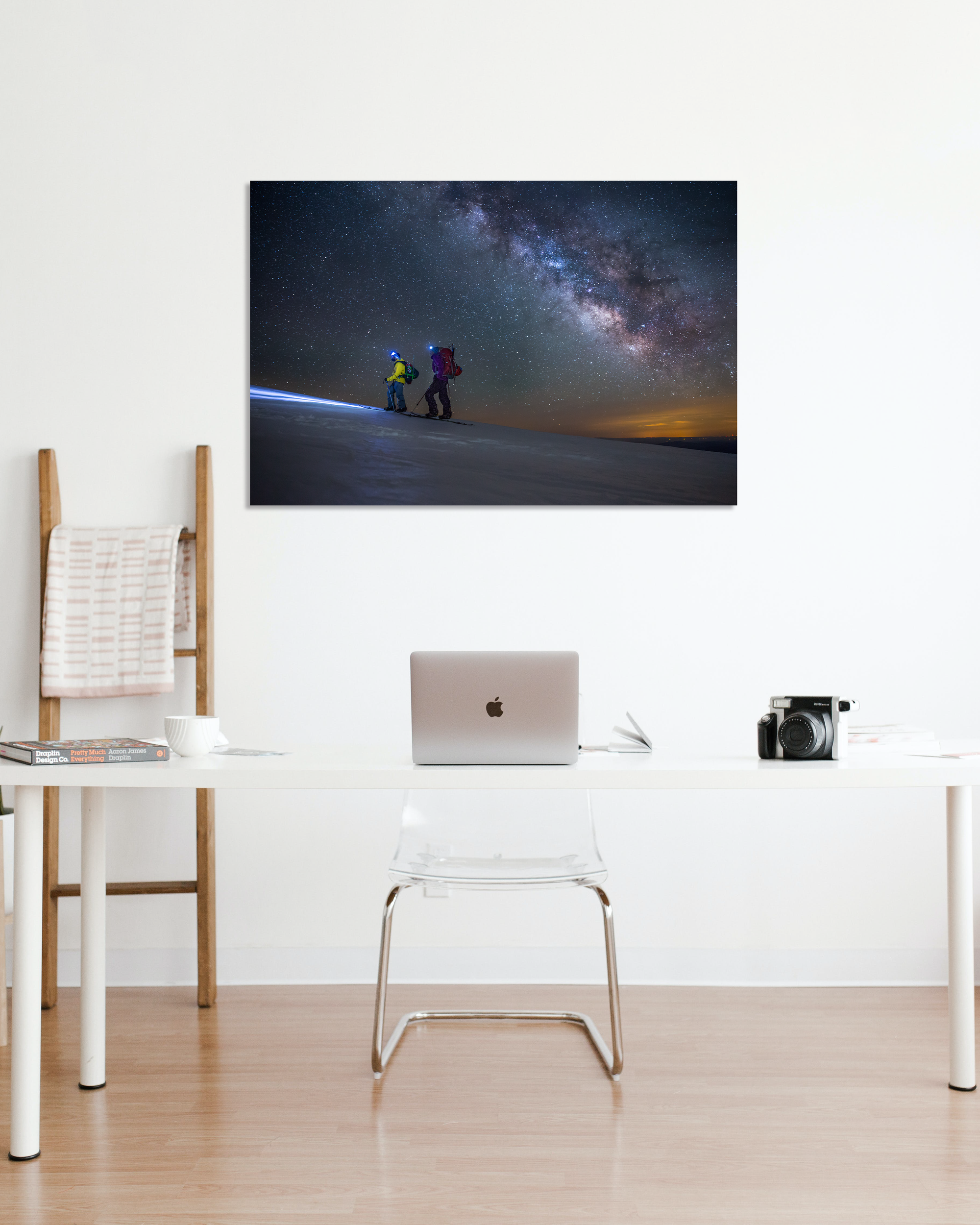 A photograph showing two climbers walking up California's Mt. Shasta under the Milk Way hangs above a small desk.