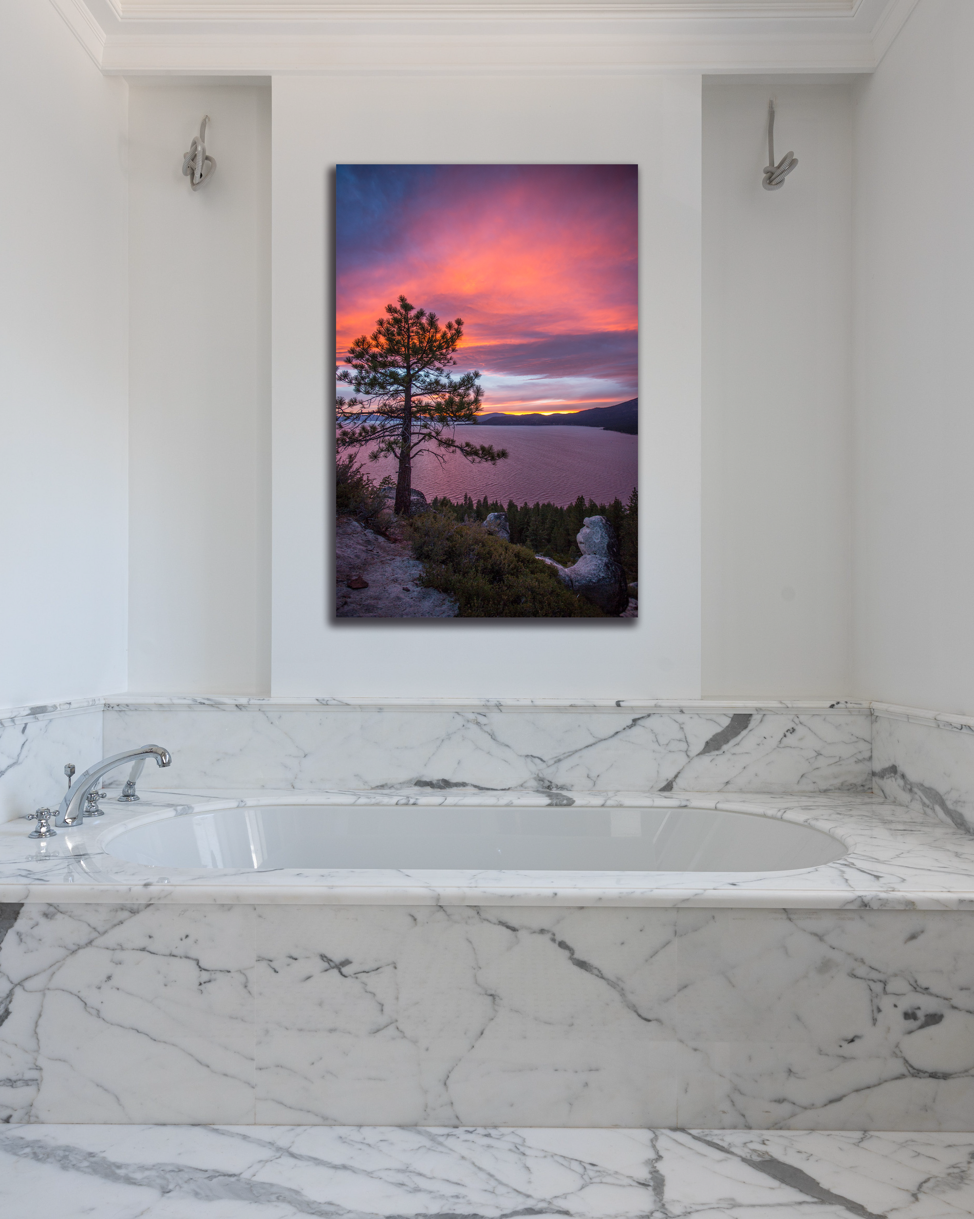 A bathroom wall is decorated with a photograph depicting a vibrant pink sunset over Lake Tahoe.