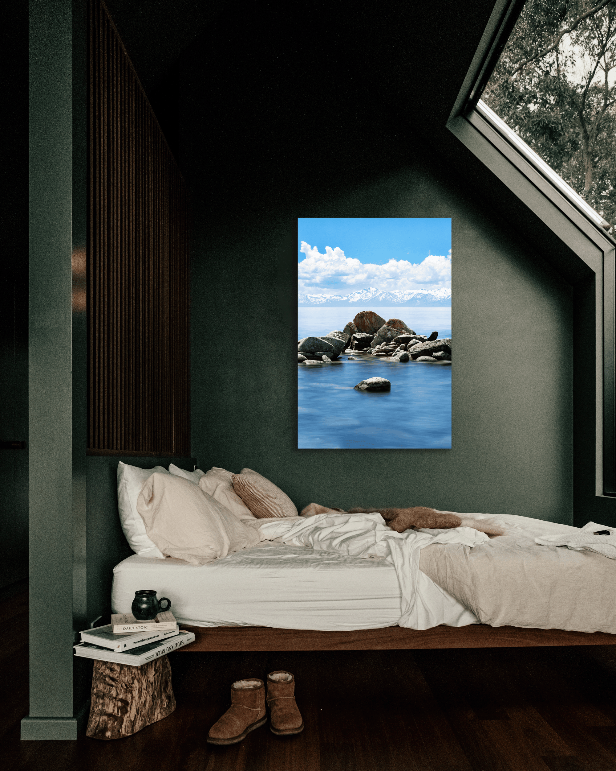 A bedroom wall is decorated with a photograph showcasing the blue waters of Lake Tahoe surrounding a granite rock formation.