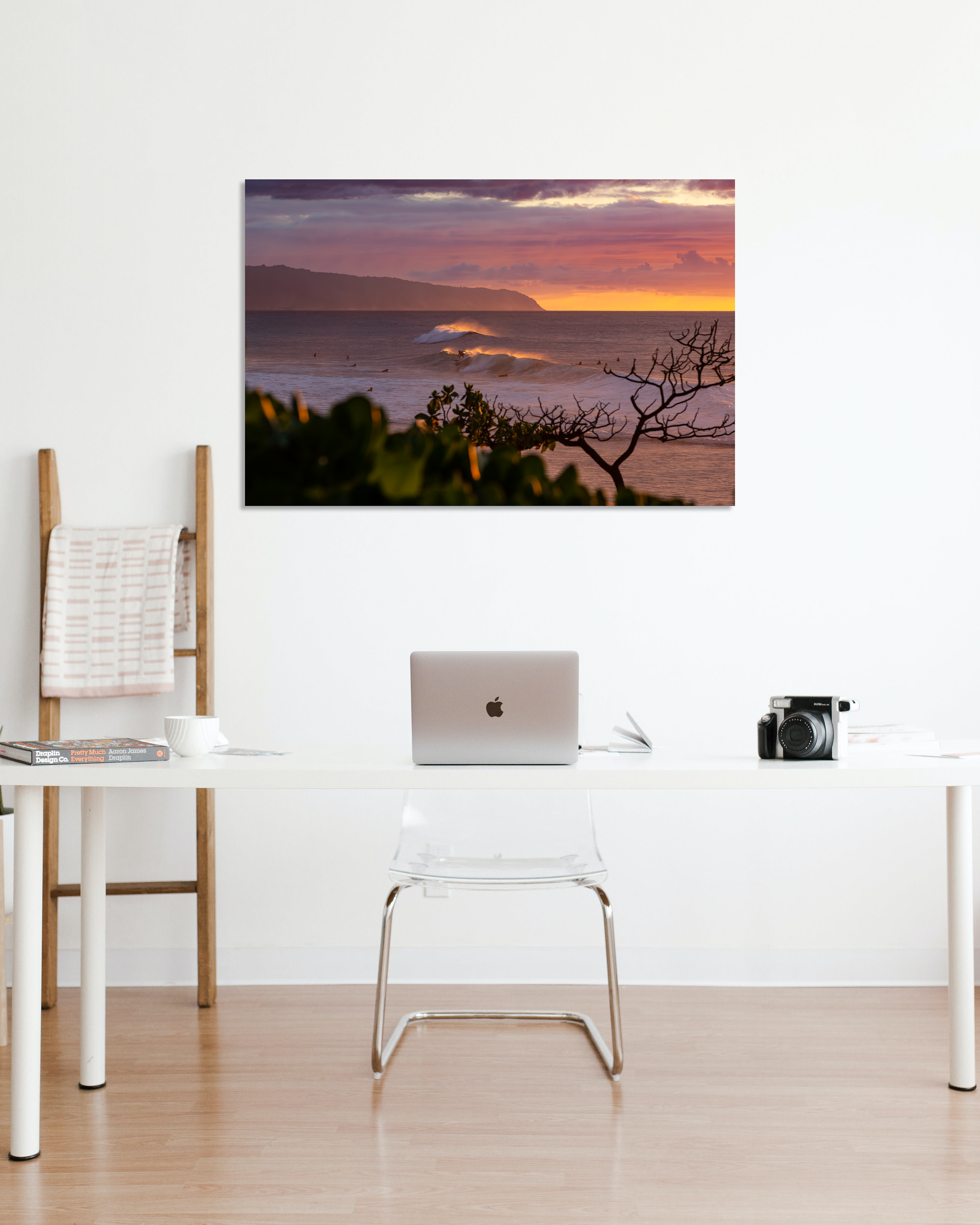 A fine art print showcasing surfers at sunset hangs above an office desk.