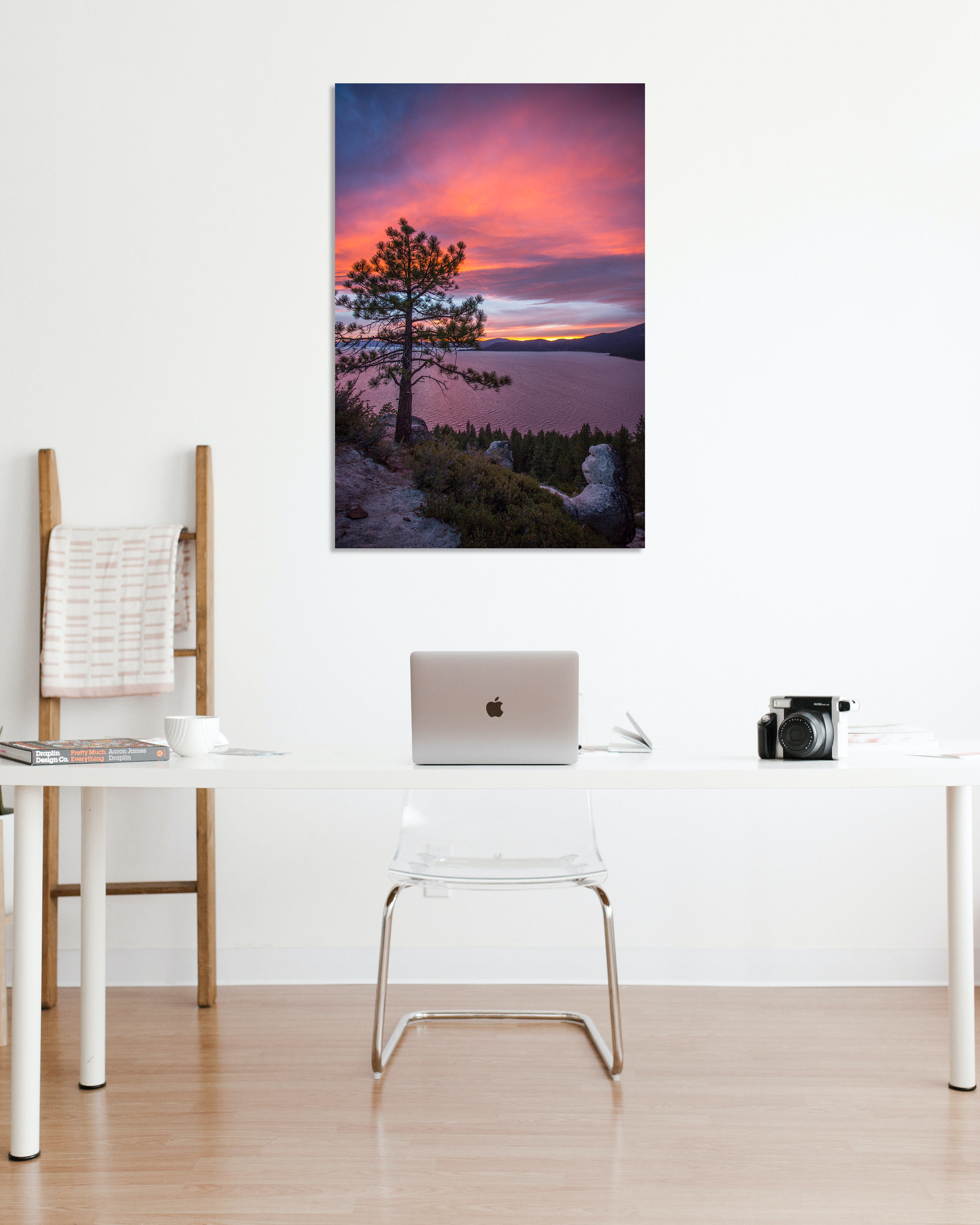 A hot pink sun setting over a lake hangs in a stark white office wall.