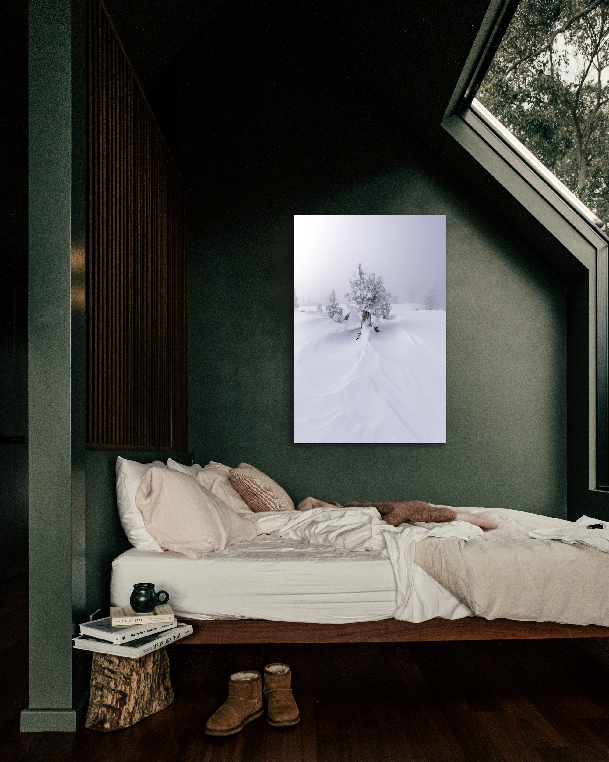 A snowy image of trees hang on a green wall illuminated by a bedroom wall.