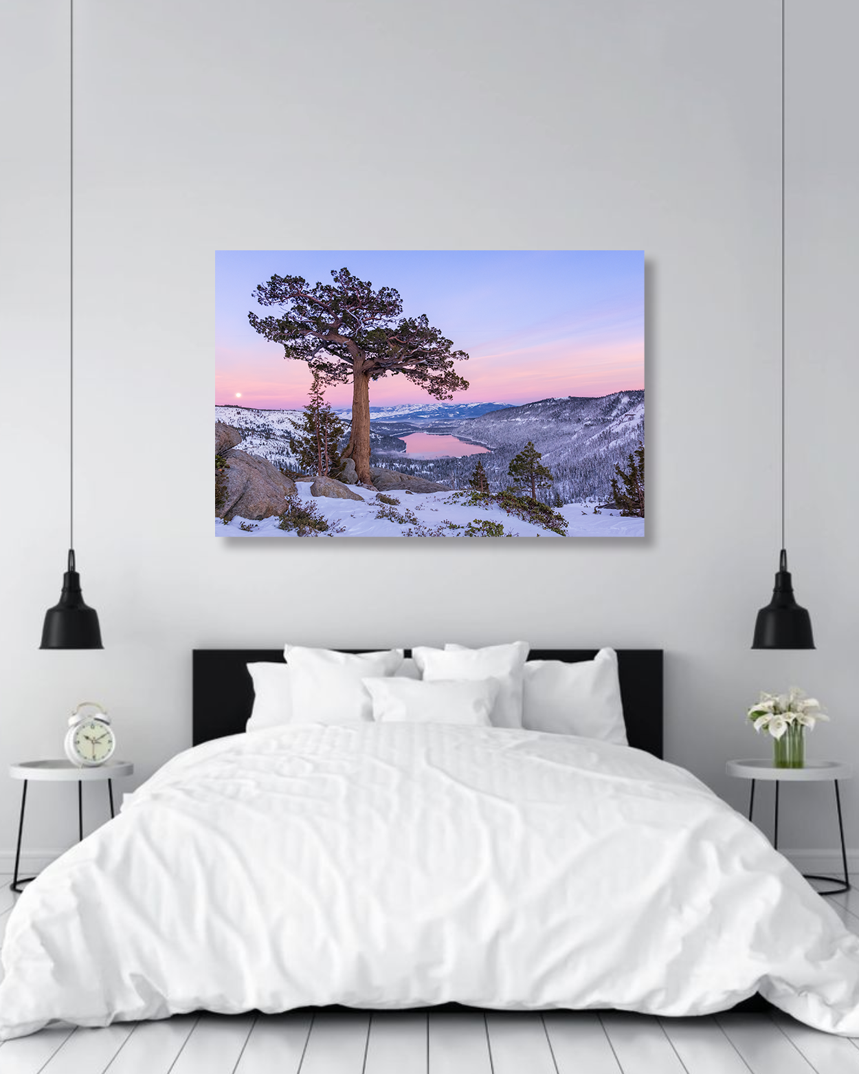 A lone tree sunset photograph hangs above a bed.