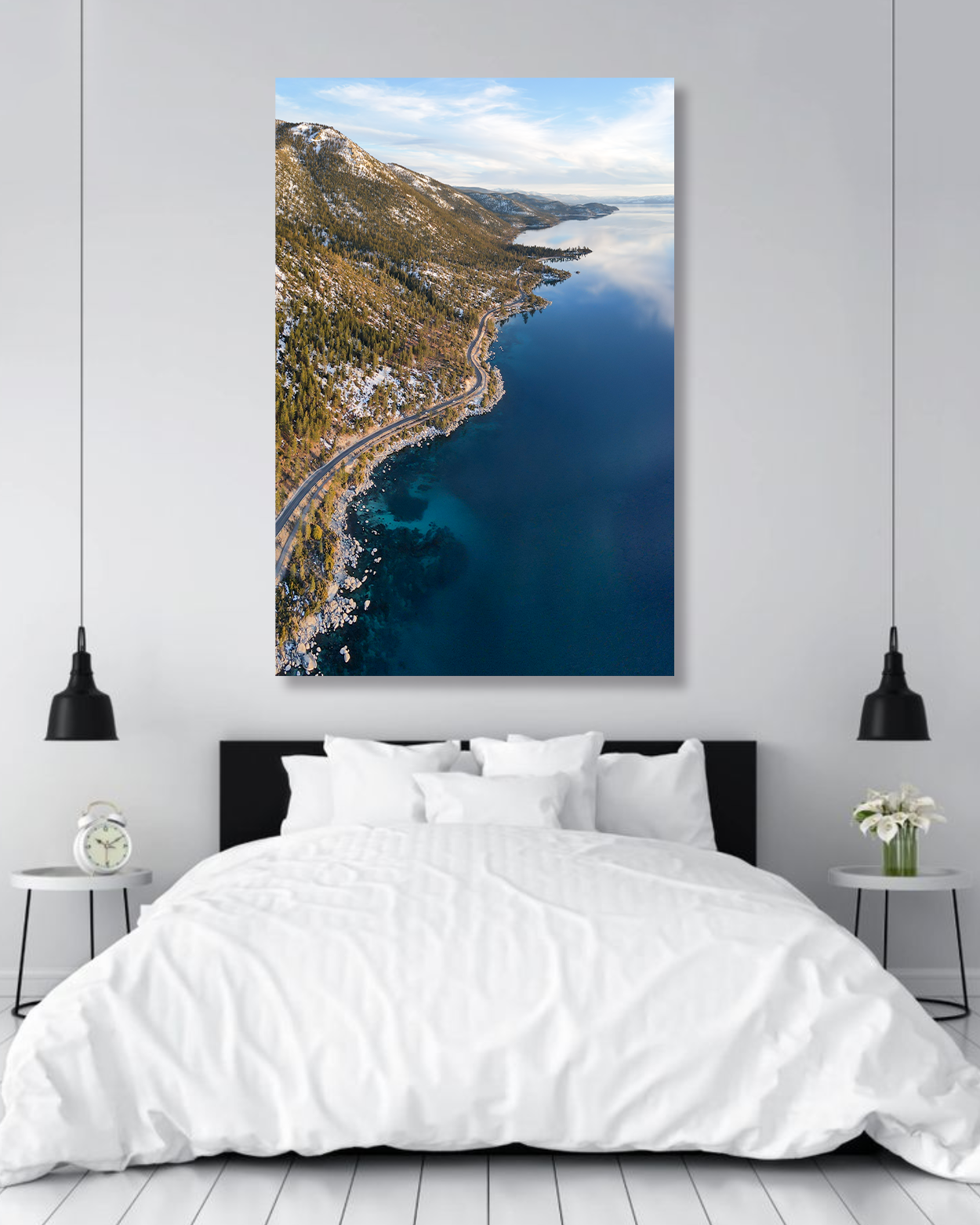 A tall photograph of the shores of Lake Tahoe hang above a bed.