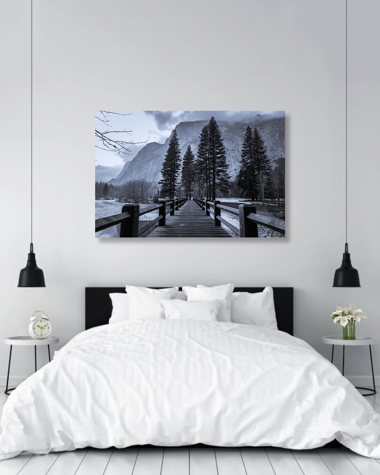 A black and white photograph of Yosemite Valley hangs above a large bed.