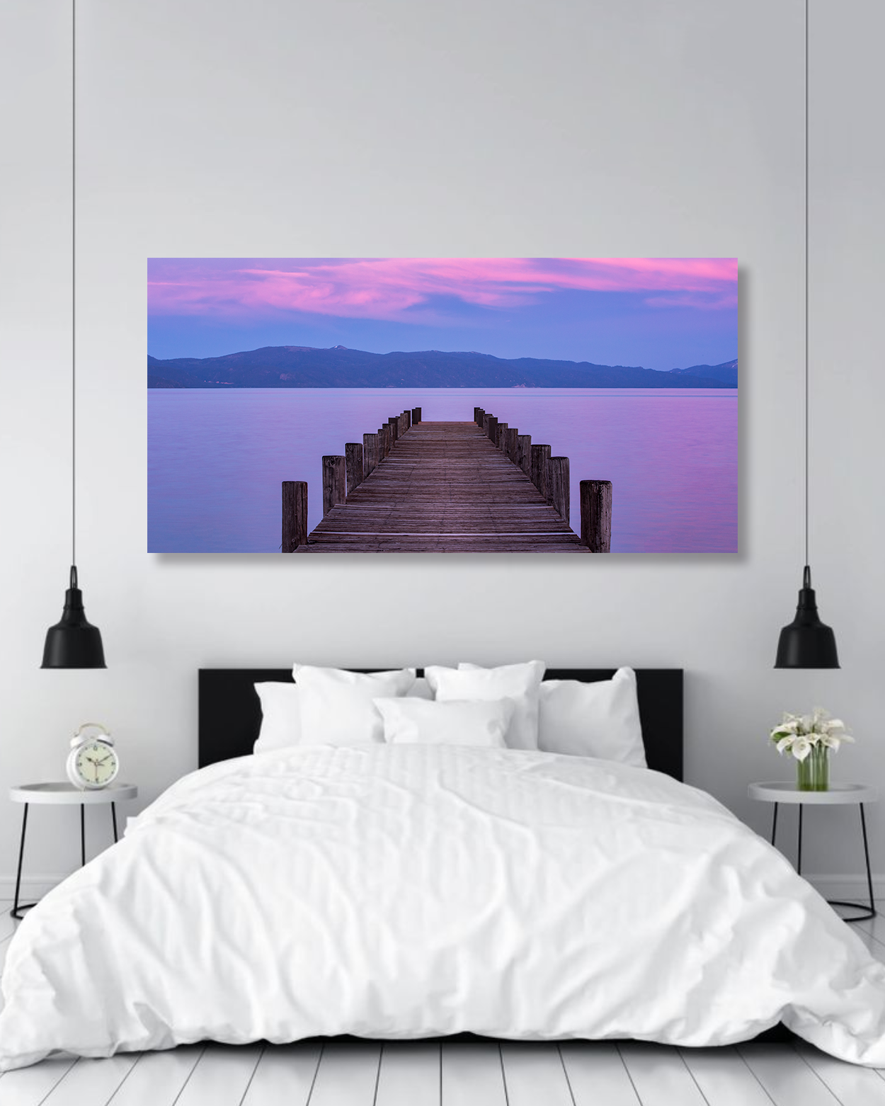 A fine arts image of a dock in Lake Tahoe at sunset hangs above a large bed.