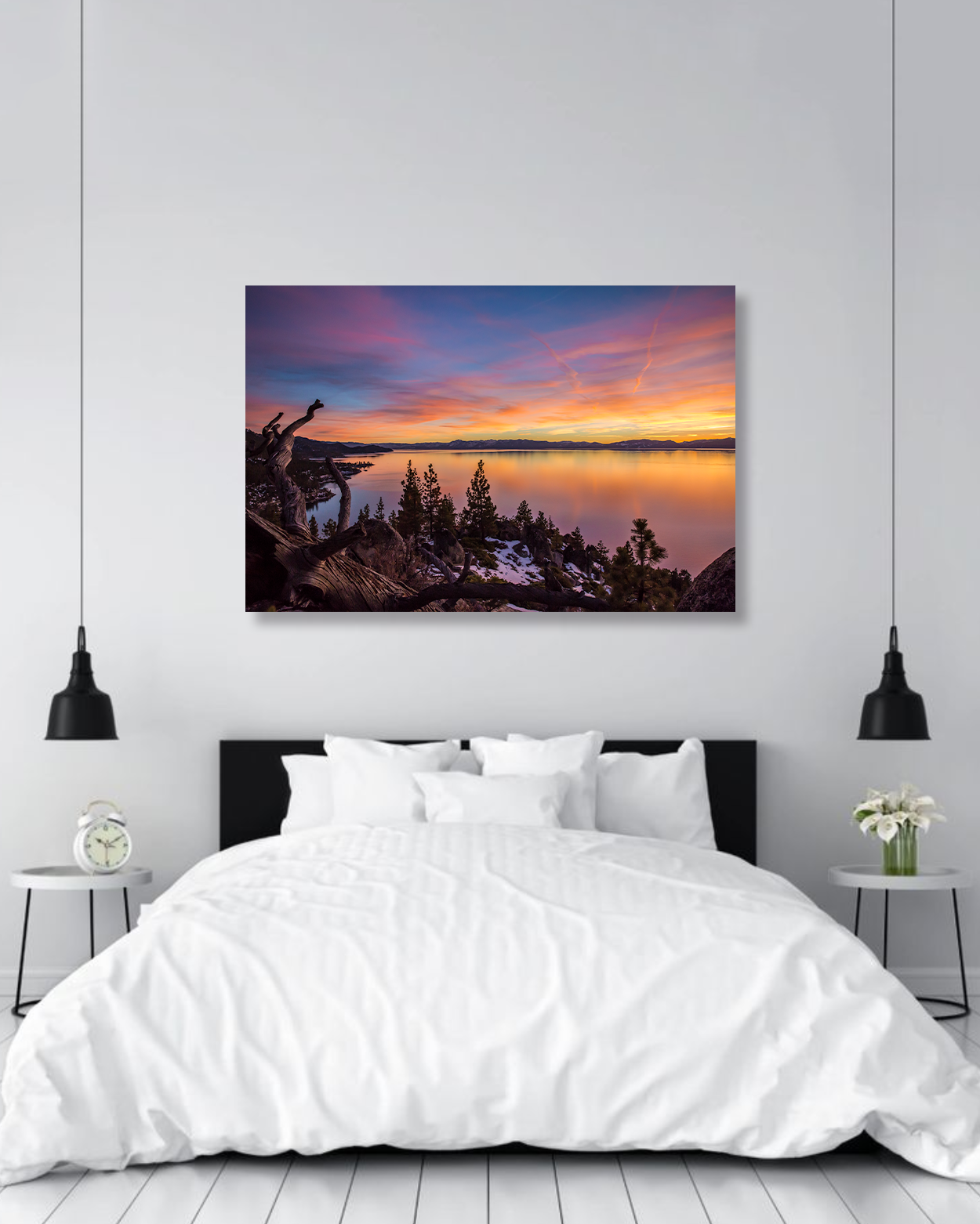 A pink hued sun set photo hangs above a crisp white bed with a black headboard.
