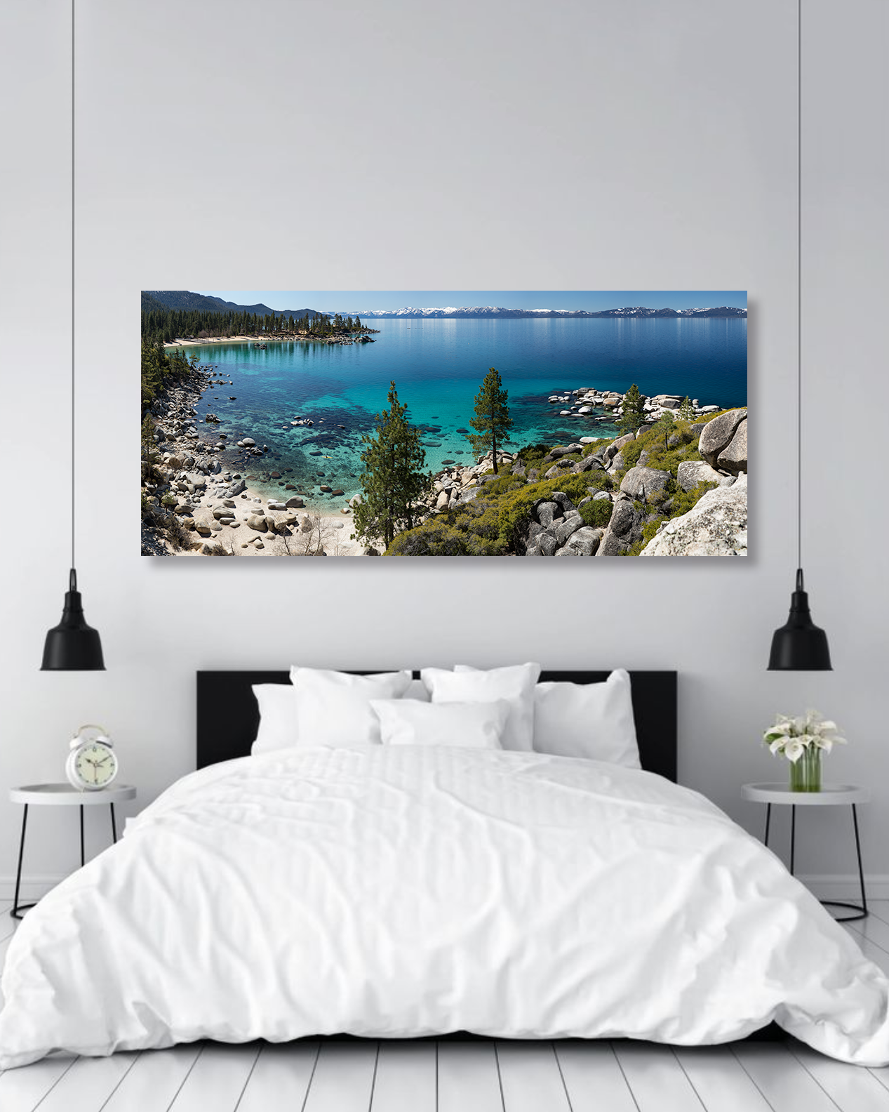 Two hanging lamps frame a photo of Lake Tahoe on a wall above bed.