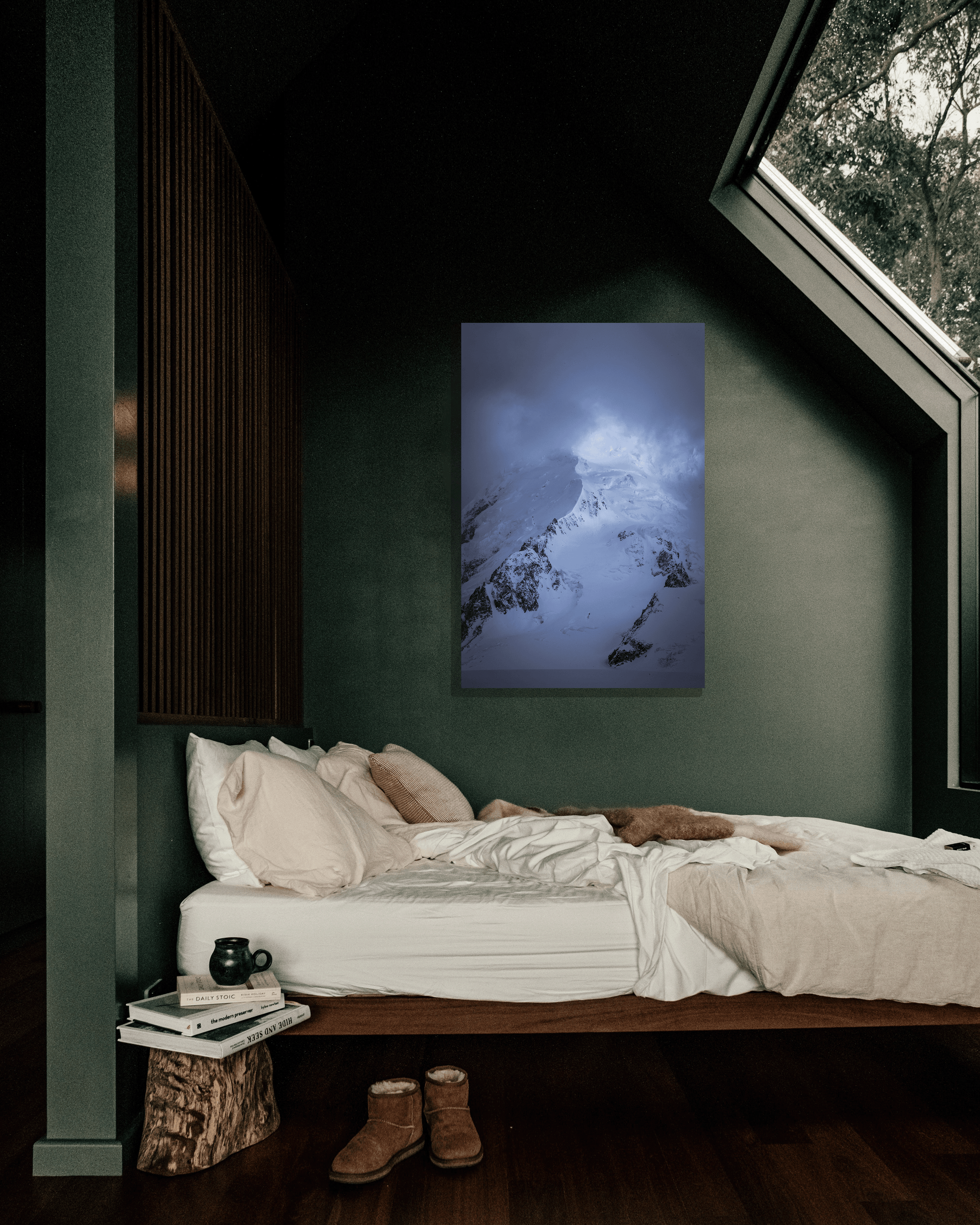 A photograph depicting an Alaskan peak melding with the fog hangs on a green wall in a cozy bedroom.