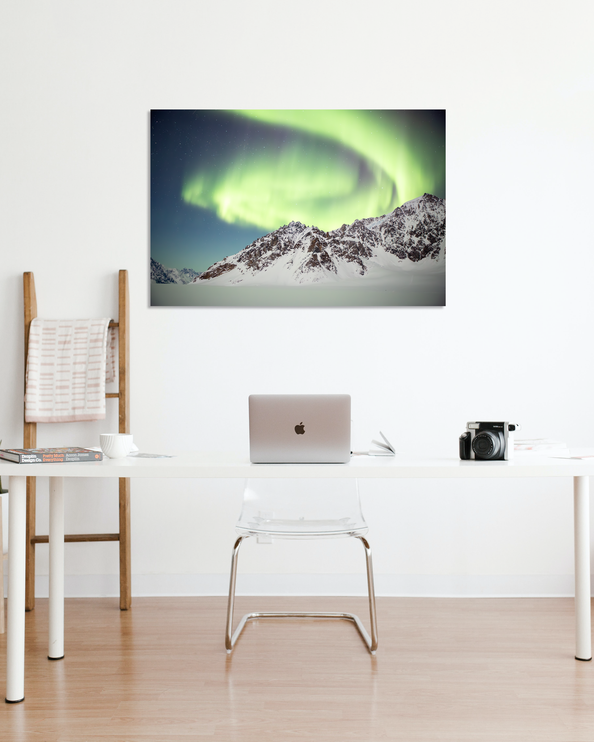 The Aurora Borealis dances above snow capped peaks in a photograph hanging on an office wall.