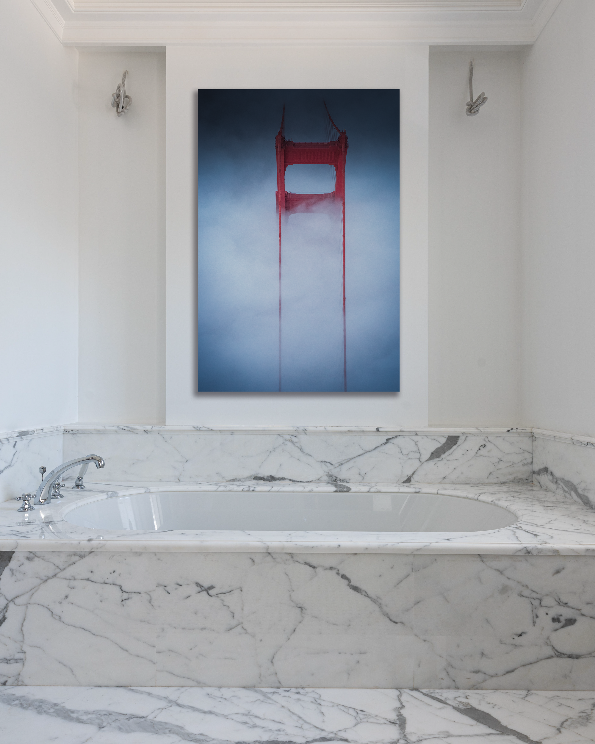 The Golden Gate Bridge peeks out of the fog in a fine art photograph hung above a marbled tub.