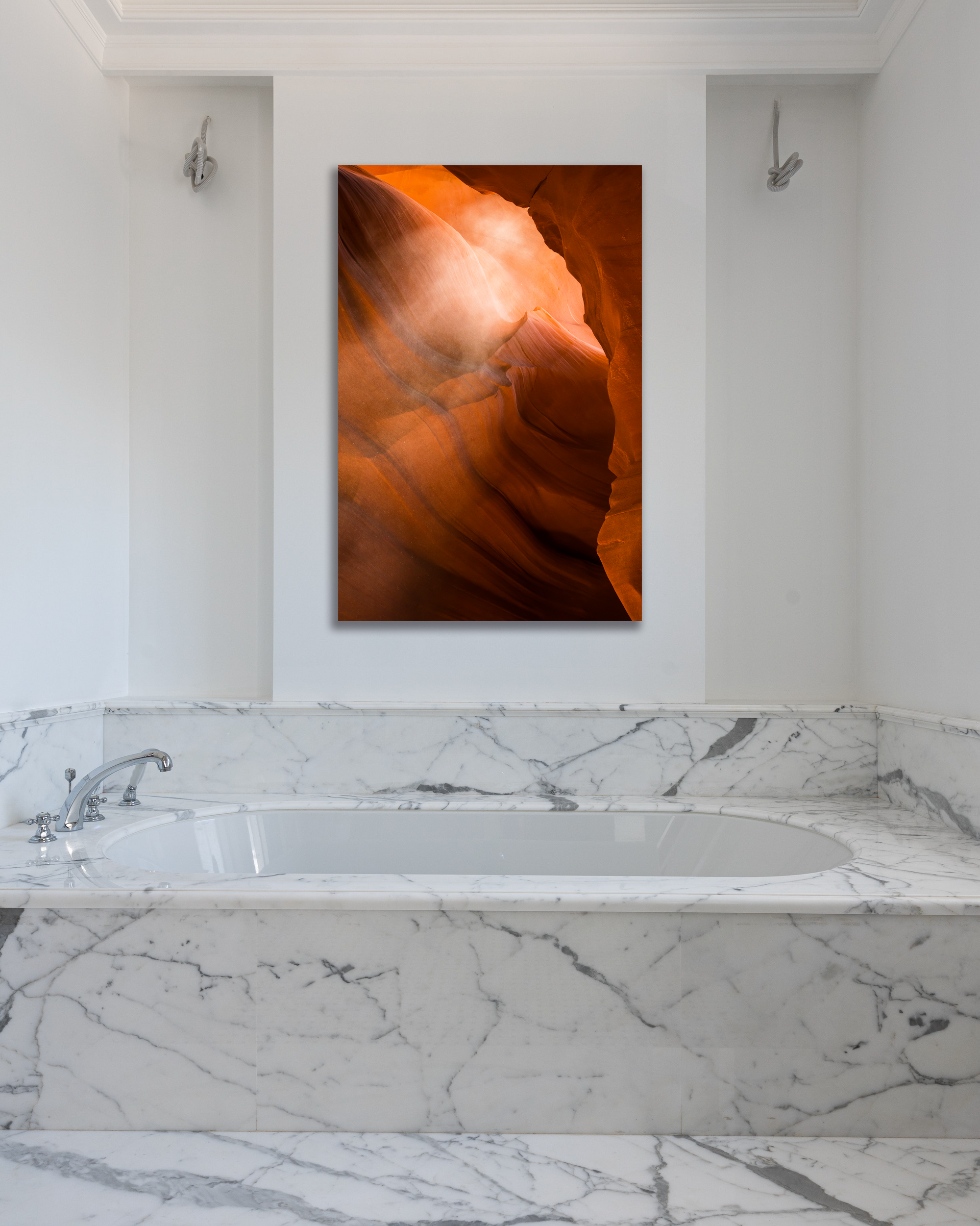 The vibrant orange canyon walls Antelope Canyon are showcase in a photograph hung above a marbled bathtub.