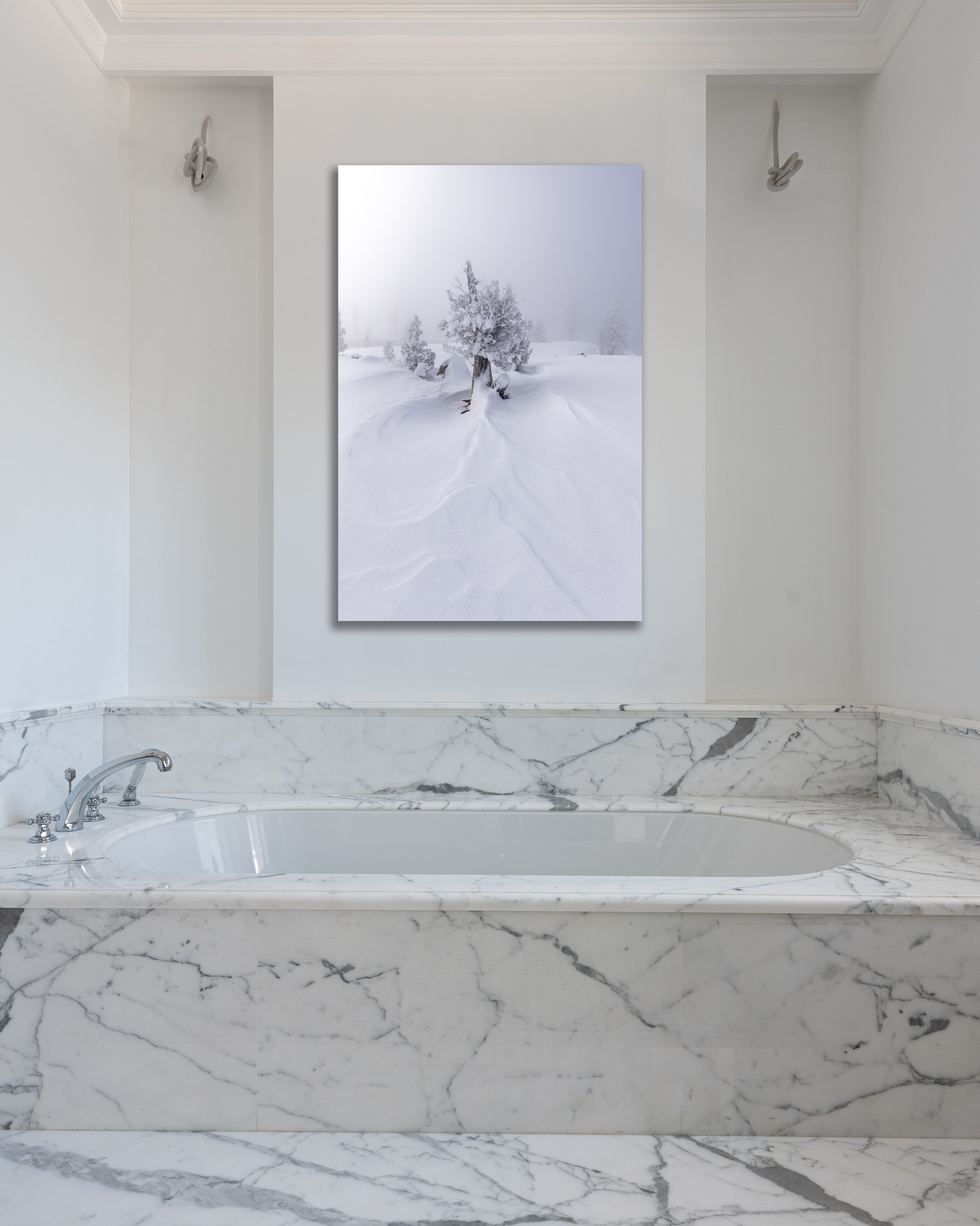 A lone juniper tree dressed in snow is highlighted in a photograph above a marbled bathtub.