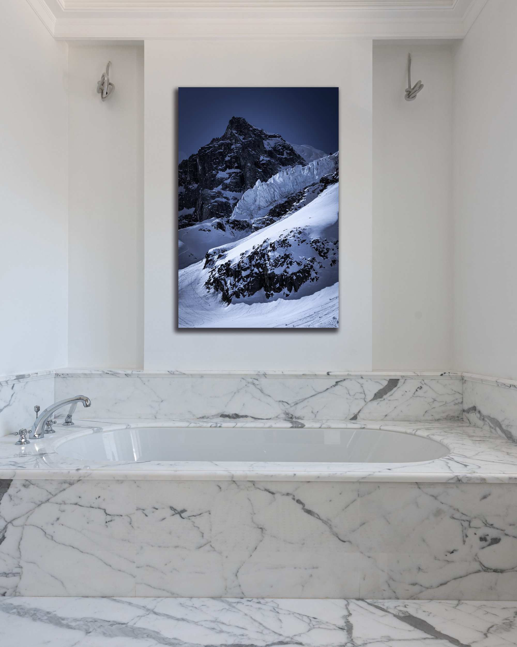 The wall above a marble tub is decorated with a photo of an Alaskan Glacier.