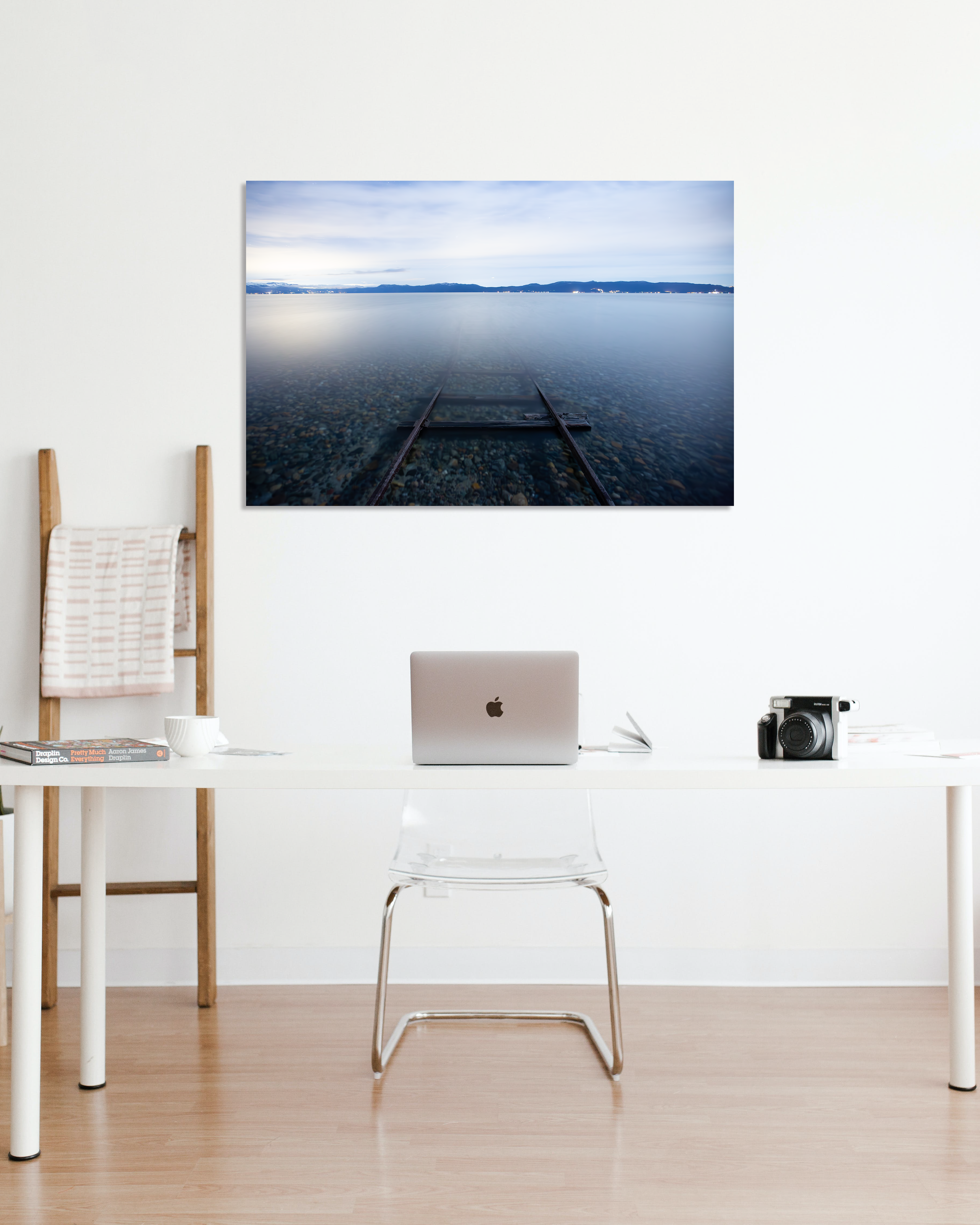 A fine art photograph showing train track disappearing into a lake hangs on an office wall.