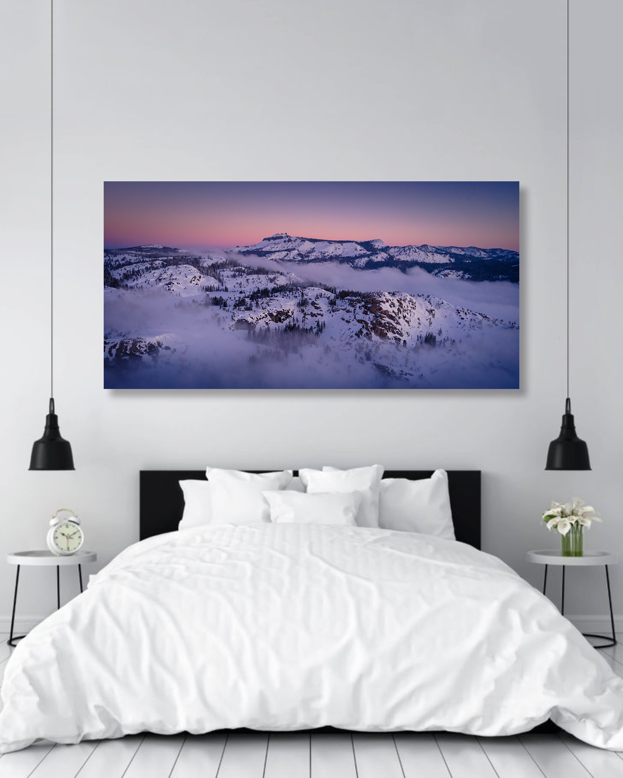 A bedroom wall is decorated with a fine art photograph showcasing snowy mountains under a pink sunset.
