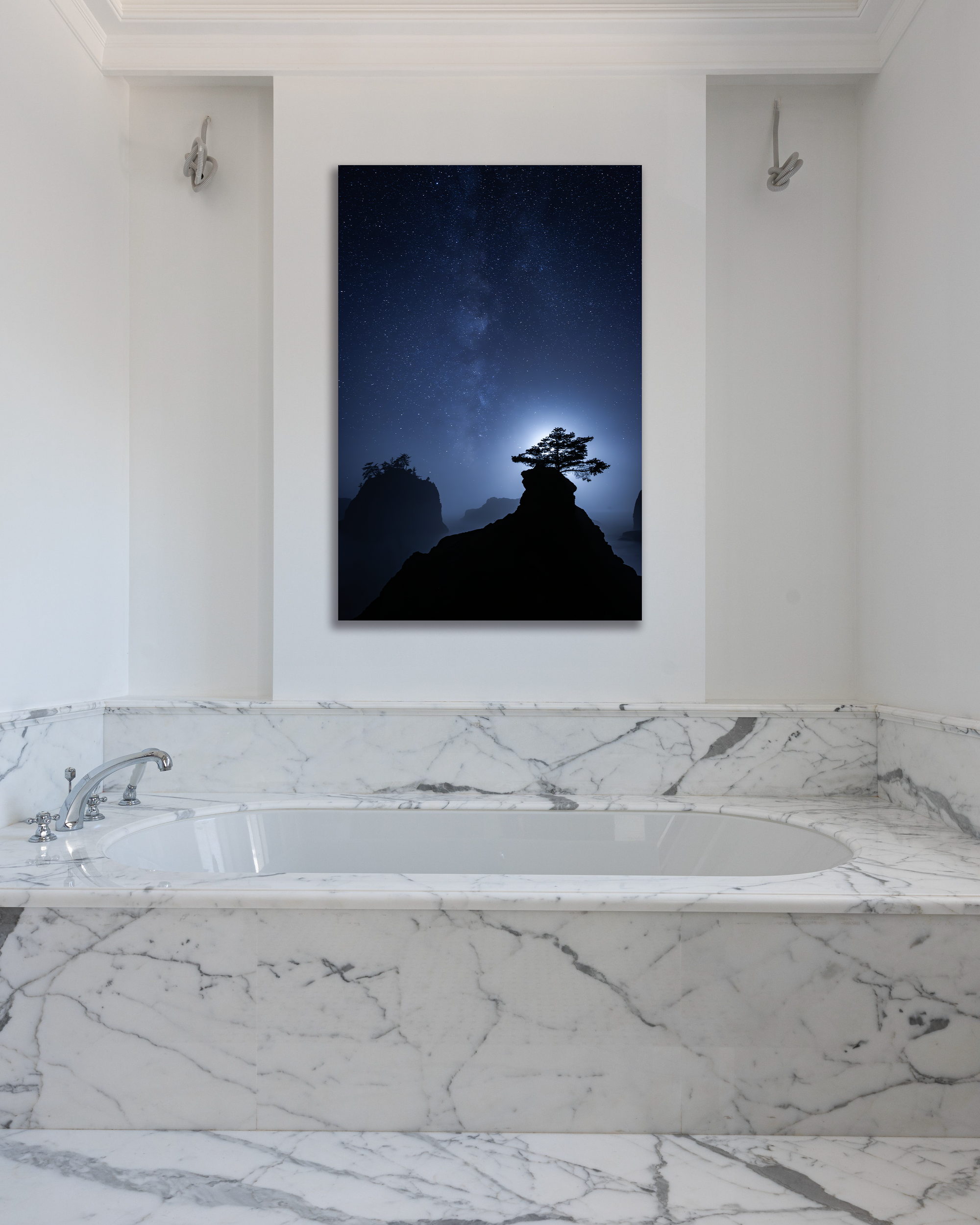 A photograph of the Milky Way with mountain peak and tree silhouettes hangs on a bathroom wall.
