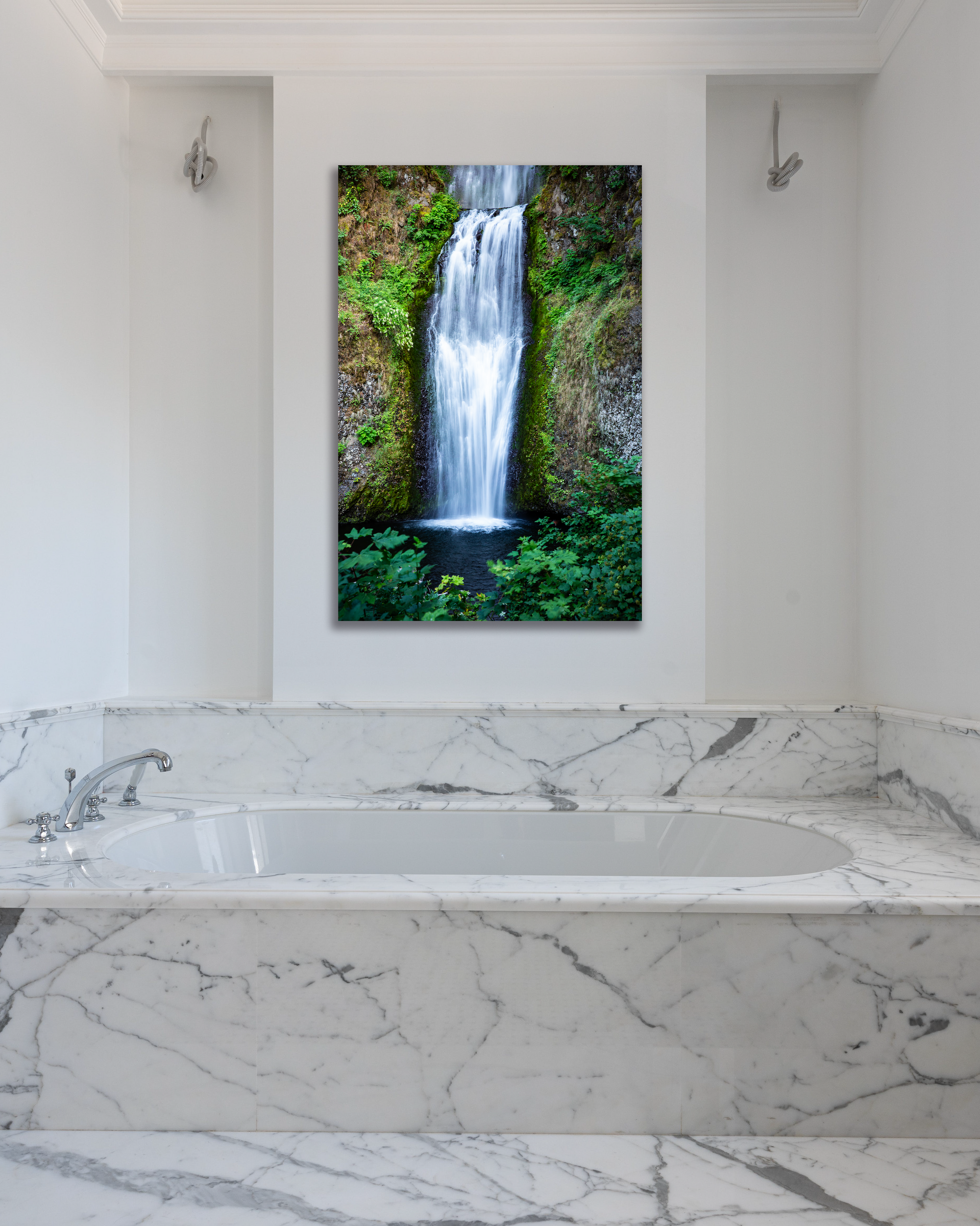 A wall behind a marbled tub  is decorated with a fine art photo showcasing Oregon's Multnomah Falls.