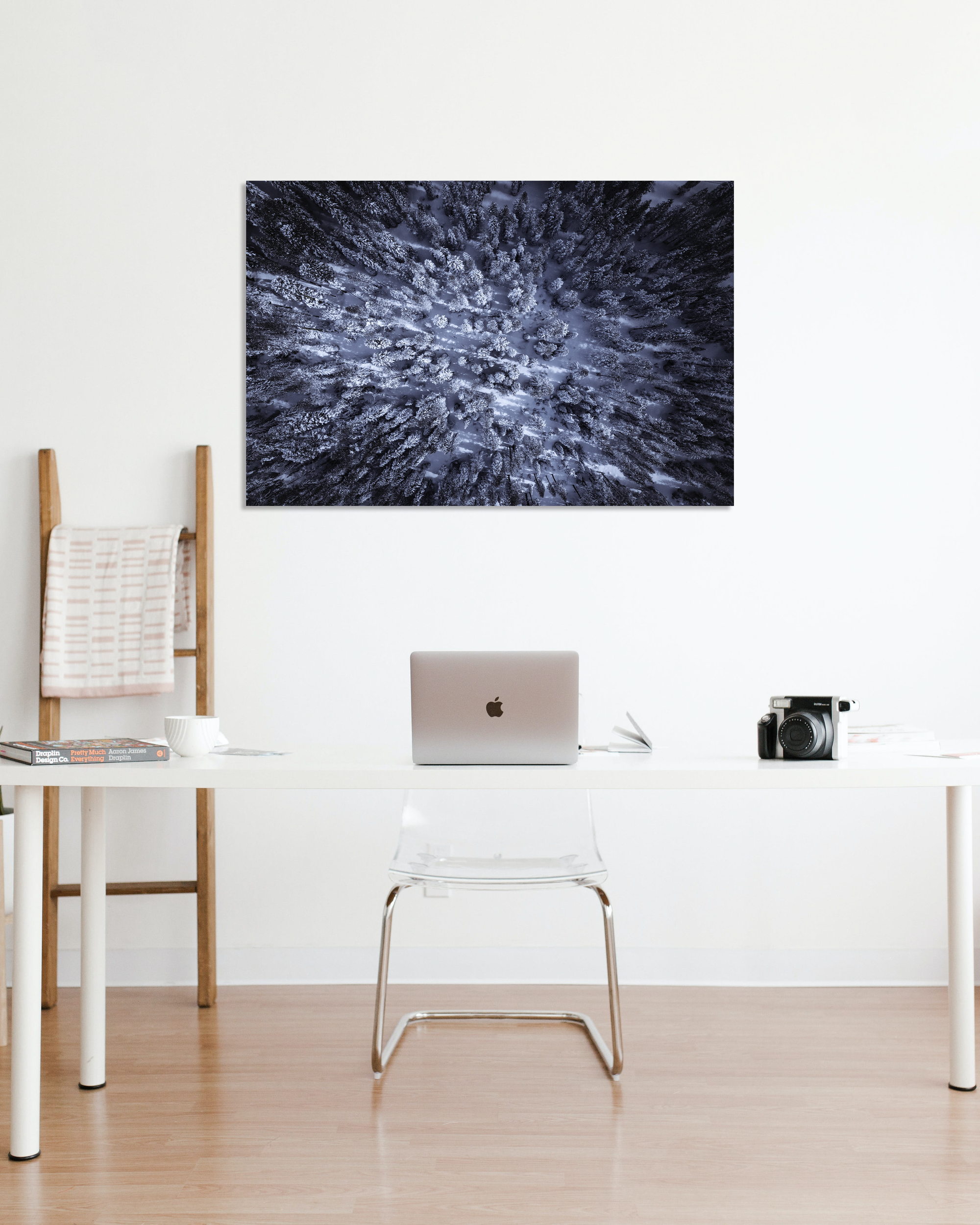 A small office is decorated with a birds eye view photograph of snow laden pine trees.