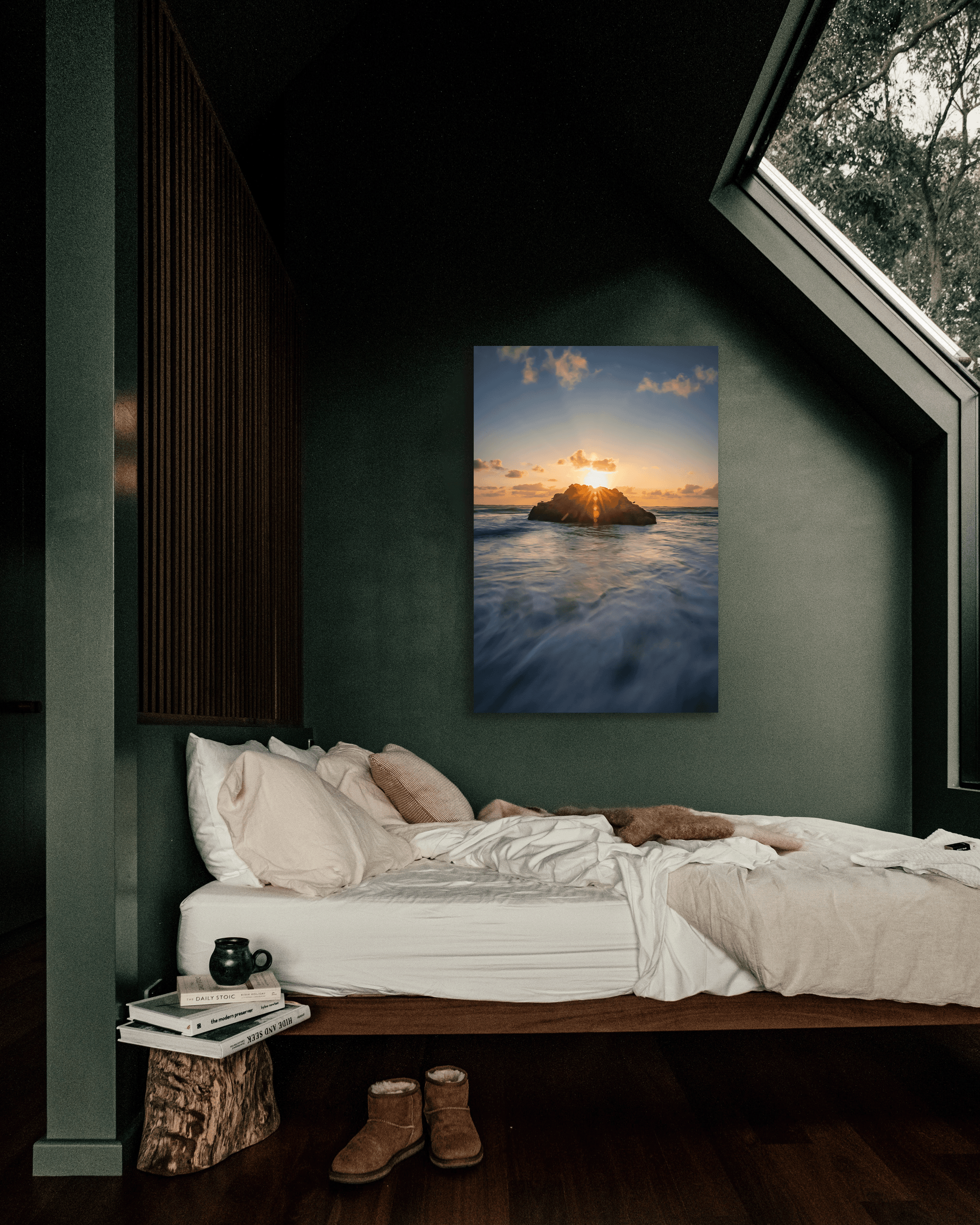 A bedroom wall showcases a fine arts photograph with two rocks with the sun setting behind them as the tide rolls around them on the Pacific coast.