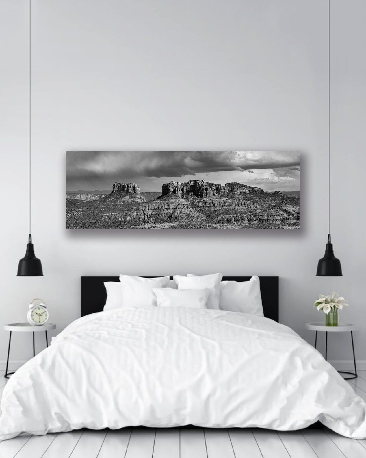 A black and white fine arts photograph of the Arizona desert hangs above a neatly made bed.