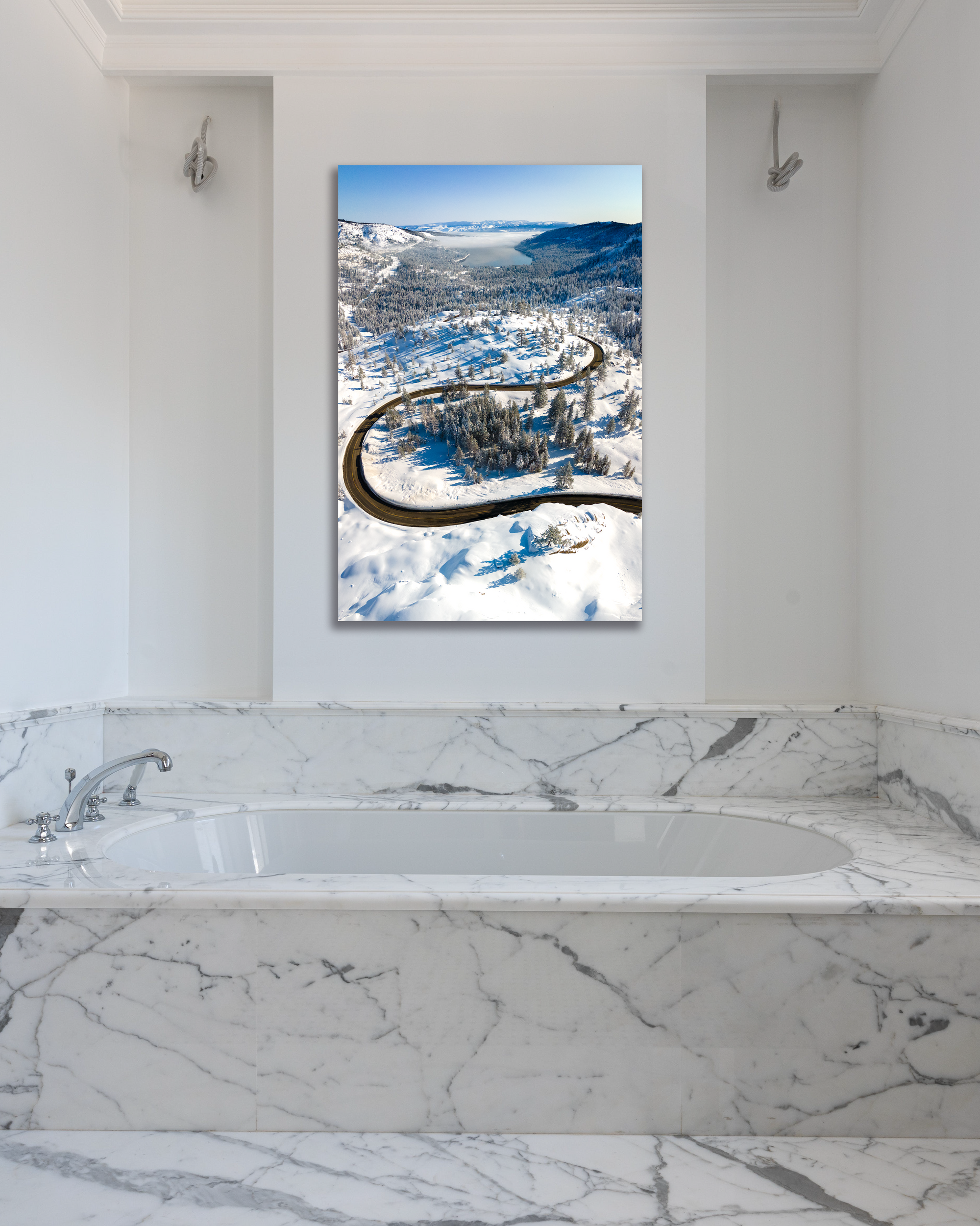 A highway winds down a snowy hillside towards Donner Lake in this fine arts photo hung above a bathtub.