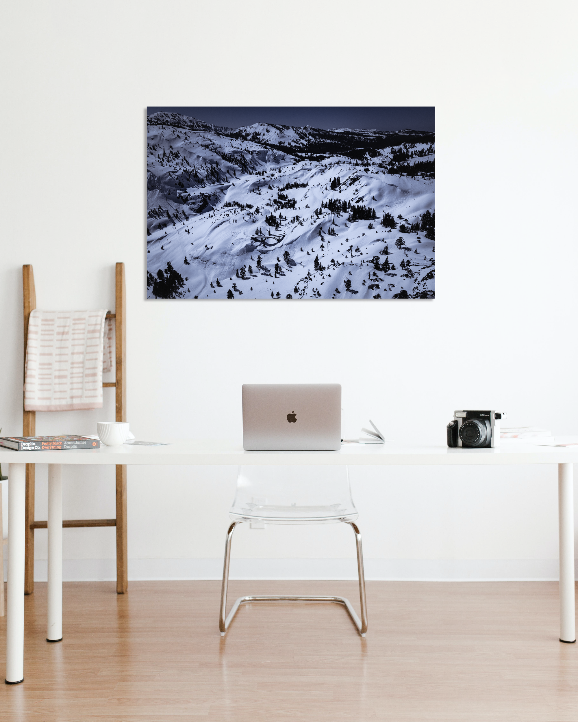 A snow photograph hangs above a minimalist desk.