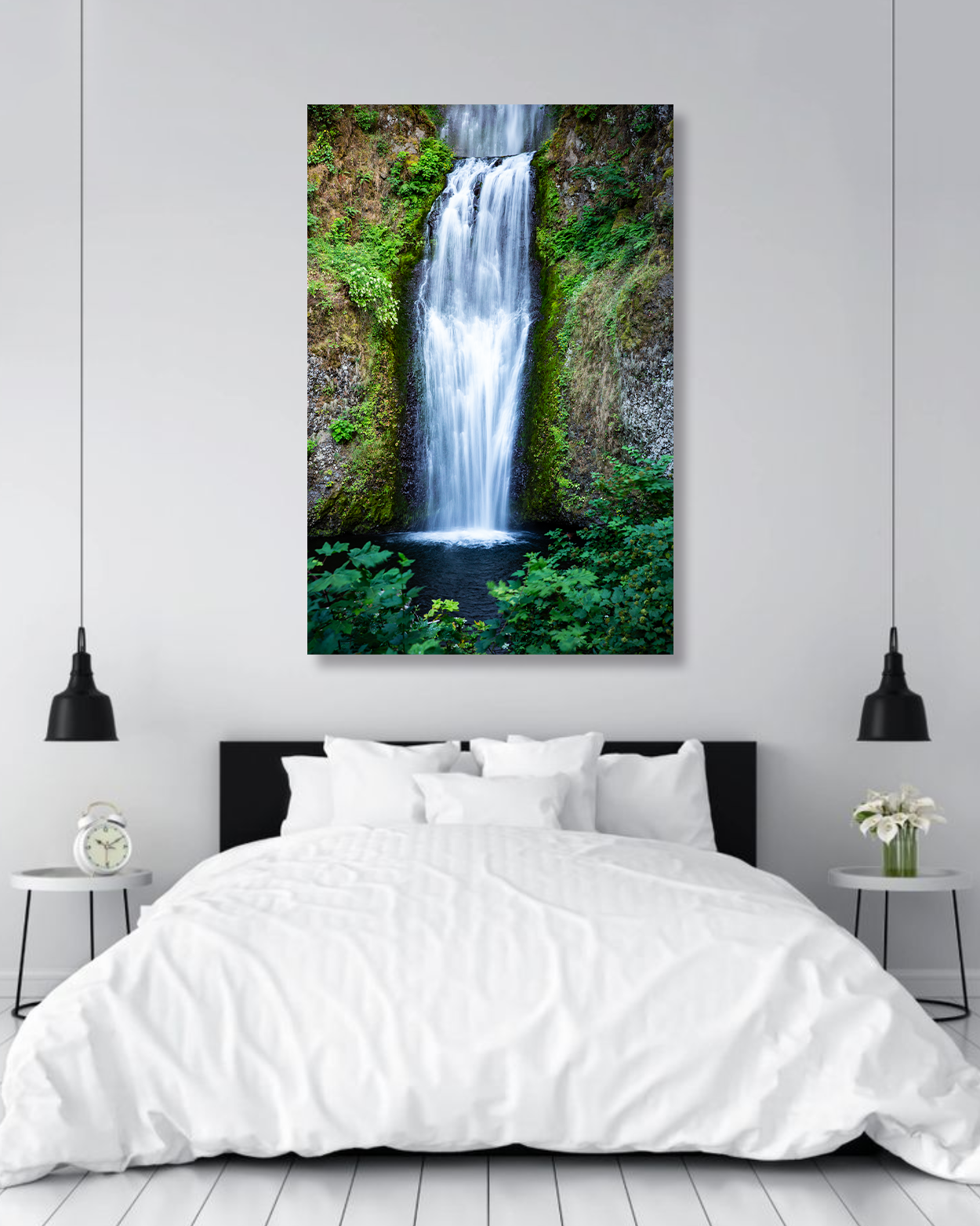 A photograph of a waterfall surrounded by lush greenery hanging on a wall in a bedroom.