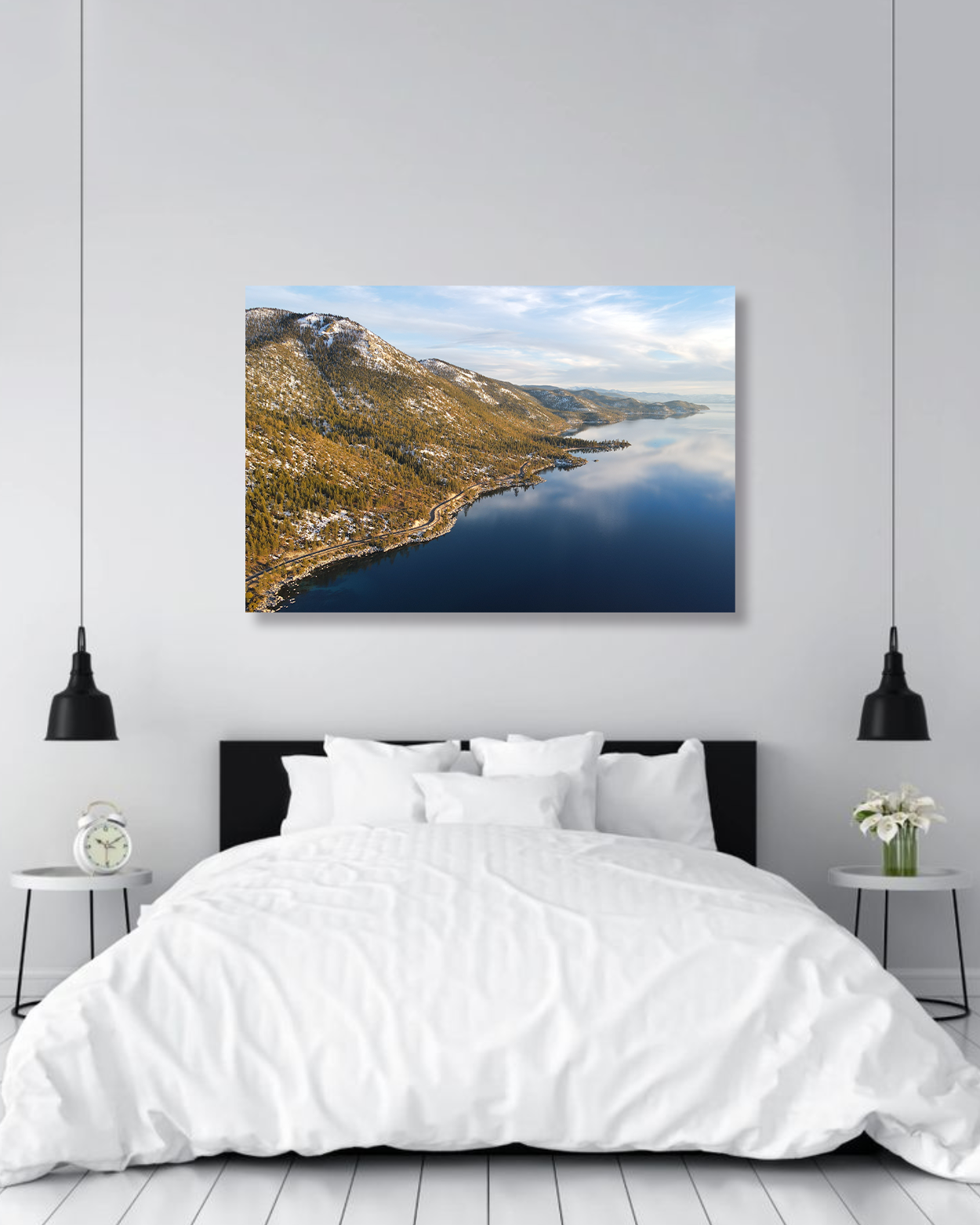 A large photograph of mountains and a lake hang above a king sized bed.