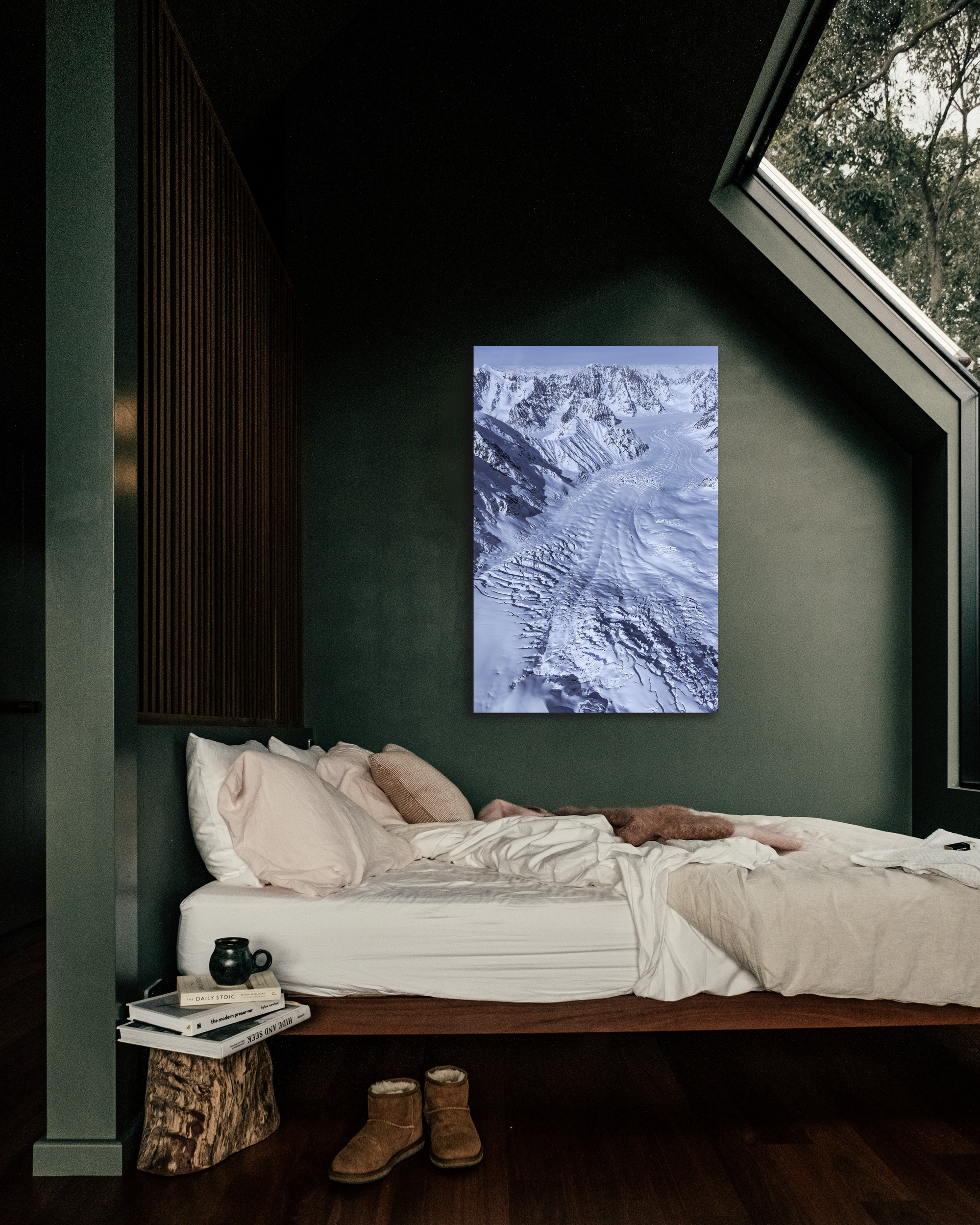 A photograph print of a glacier hangs on the wall of a small bedroom.