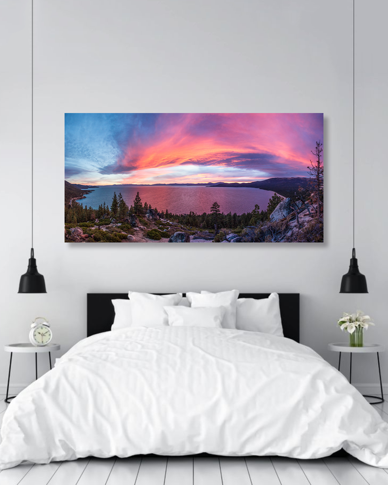 A large photo print of a vibrant pink sunset over Lake Tahoe hangs on the wall of a bedroom.