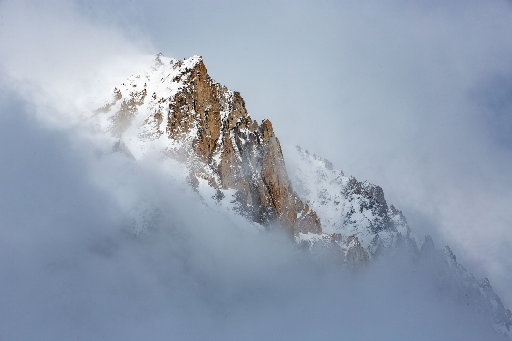 Fog blankets tall mountain spires.