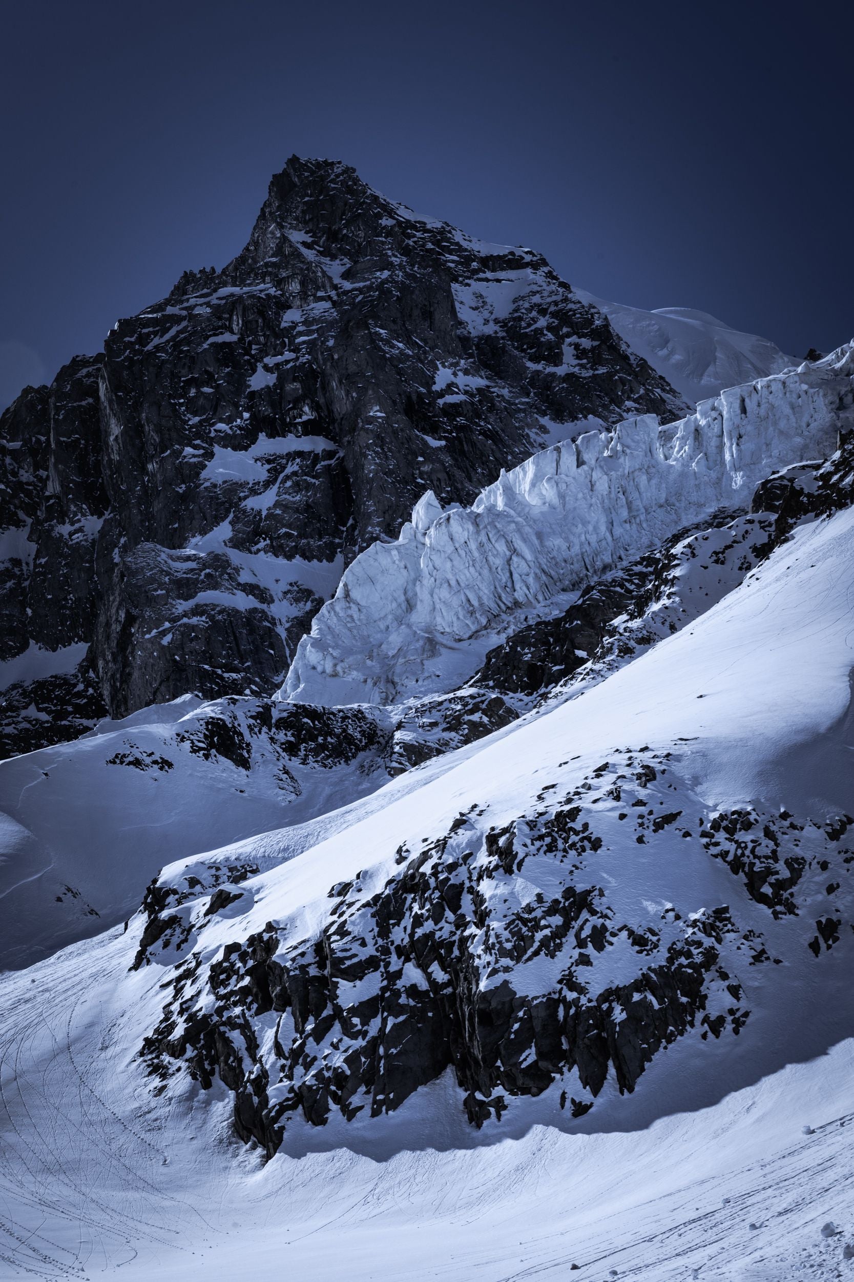 A glacier sits below a jagged rocky peak.