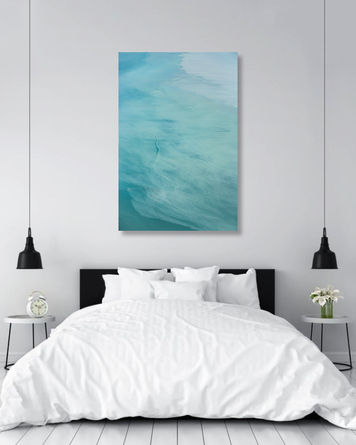 A large photography print of turquoise water hangs above a bed.