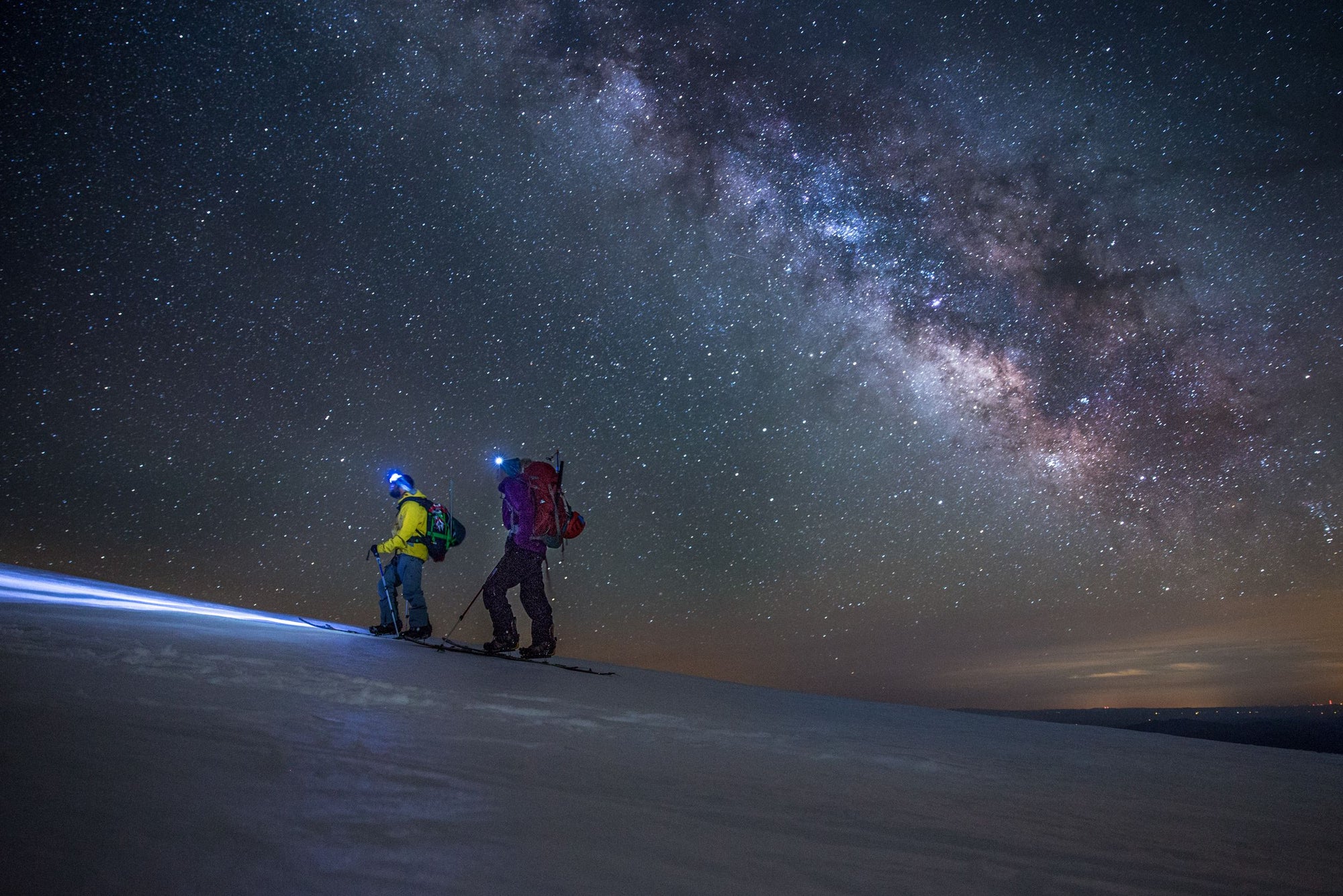 Two splitboarders skin up Mt.Shasta under the Milky Way.