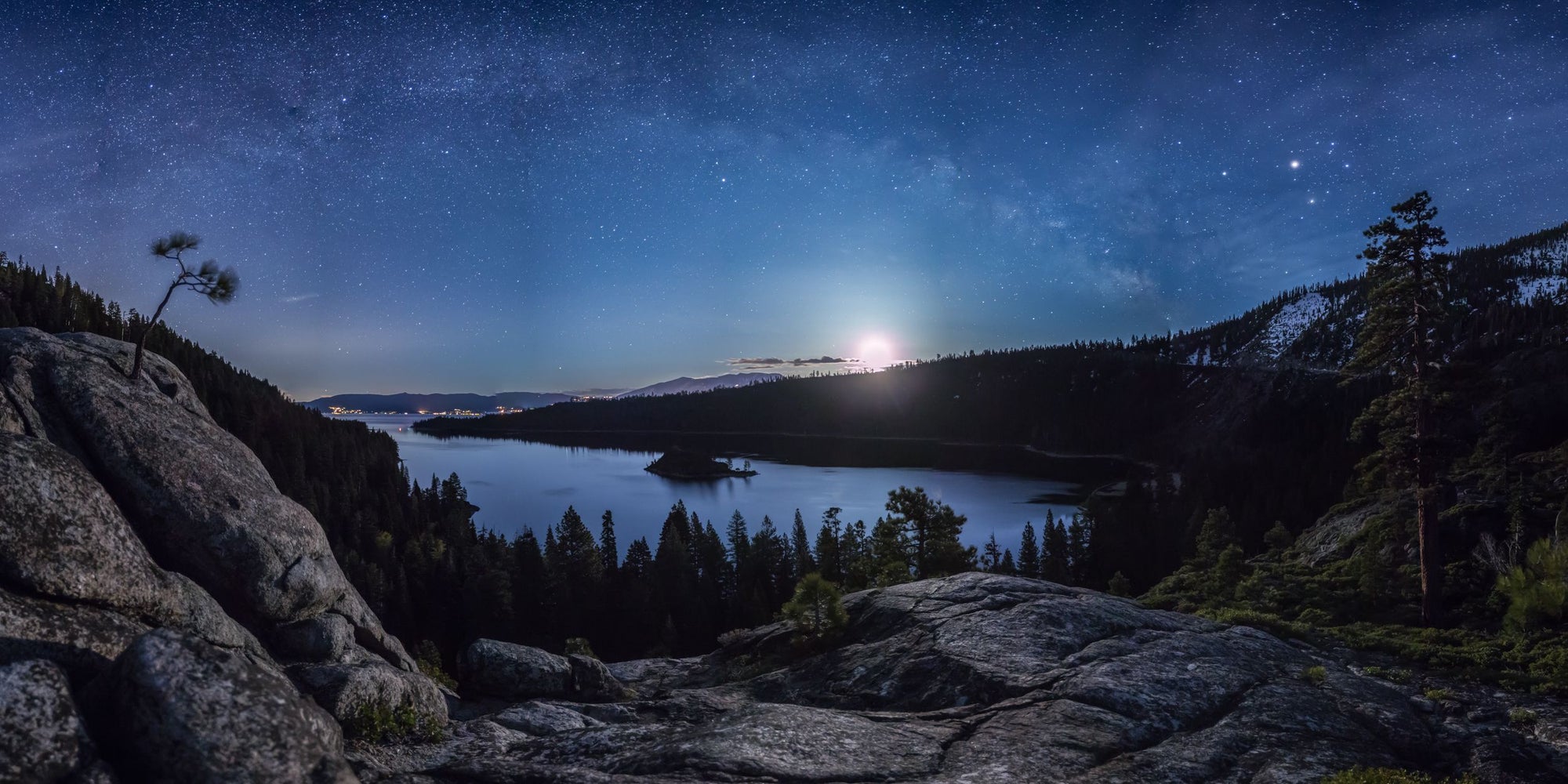 The moon rises over Emerald Bay in Lake Tahoe as the Milky Way arches above.